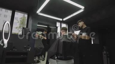 男式理发用电动剃须刀.. 理发师在理发店为顾客理发. 男子